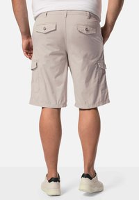 Helle beige Cargo-Shorts mit zwei Gesäßtaschen und seitlichen Cargo-Taschen, aus leichtem Stoff gefertigt, mit geradem Schnitt und einem Saum, der über dem Knie endet.