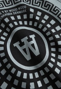 Țesătură neagră cu un logo alb circular cu inscripția "WW" în centru. Modele concentrice și designuri geometrice în nuanțe pale în jur.