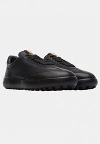 Sneakers neri low-top con suole arrotondate, lacci neri, dettagli di cucitura discreti e etichette arancioni con logo sulla linguetta, su sfondo bianco.
