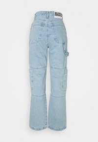 Pantalones cargo de denim azul claro con pierna acampanada, costuras visibles, múltiples bolsillos y una etiqueta en la cintura que dice "RAGGED."