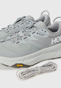Grå løpetøfler med teksturert overdel, GORE-TEX merkevare og Vibram såle. Inkluderer grå snøringer, lette med et strømlinjeformet design.
