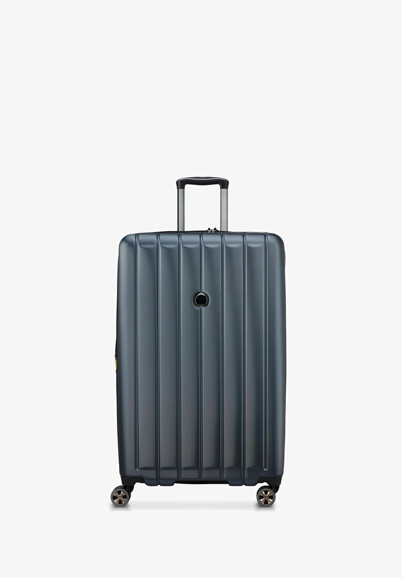 Maleta rígida de color gris oscuro, con surcos verticales, un mango telescópico y cuatro ruedas giratorias para mayor movilidad.