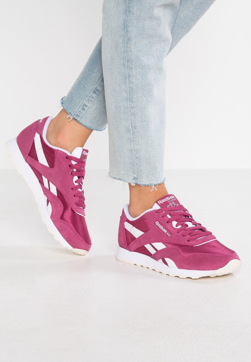Fuchsie sportovní tenisky s bílými akcenty, s semišovým svrškem, kulatou špičkou a texturem gumovou podešví. Neformální design s šněrováním.