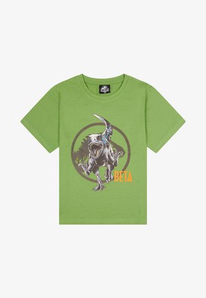 Grünes Baumwoll-T-Shirt mit einer Grafik eines sich bewegenden Dinosauriers, umgeben von einem kreisförmigen Designelement und mit dem Text "BETA" in Orange.