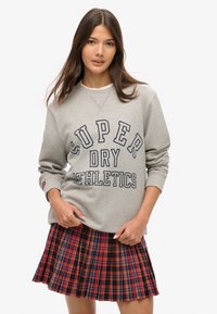 Szara bluza z nadrukiem "SUPER DRY ATHLETICS" w kolorze granatowym. W połączeniu z plisowaną spódnicą w kratę w kolorze czerwonym i czarnym. Miękki materiał, casualowy krój.