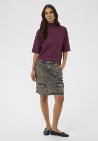 Purple cropped t-shirt with short sleeves, paired with a gray denim skirt featuring front pockets and a drawstring waist. Black flat shoes.