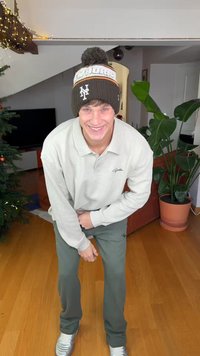 Beige langärmeliges Poloshirt, grüne gerippte Hose und eine braune gestrickte Mütze mit Bommel. Silberne Sneakers vervollständigen das Outfit.