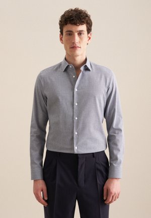 Camicia button-up azzurro chiaro con motivo a quadretti, maniche lunghe e colletto classico, abbinata a pantaloni scuri a pieghe.