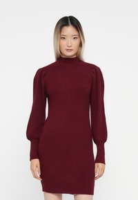 Burgundy ribbed-knit dress with long puff sleeves and a high neckline, featuring a fitted silhouette and soft texture.