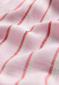 Tessuto di cotone con sfondo rosa e righe alternate rosse e bianche. Texture morbida con un aspetto leggermente tessuto.