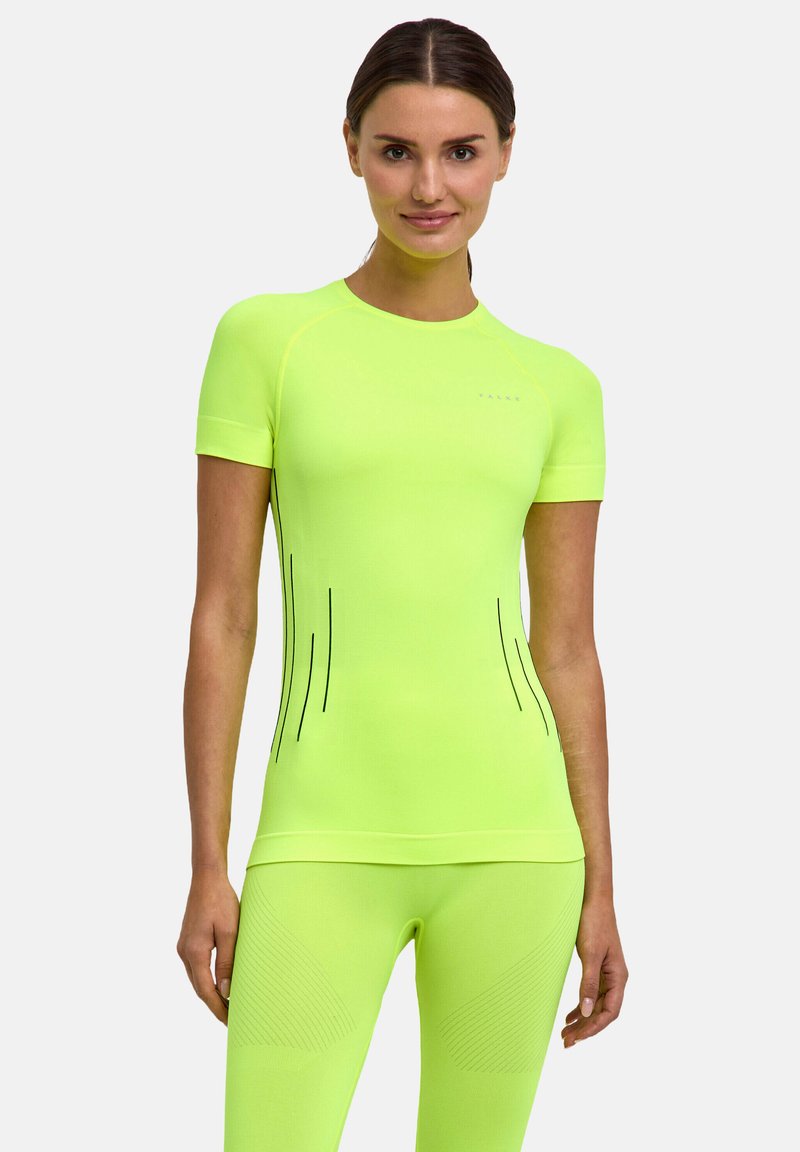 Woman wearing bright neon yellow fitted short-sleeve shirt and matching leggings, standing against a plain light gray background.