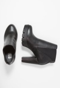 Stivaletti neri in pelle liscia con tacco spesso e testurizzato. Presentano un pannello laterale in tessuto elastico e una chiusura con cerniera.