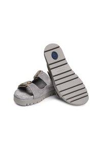 Graue Wildleder-Sandalen mit zwei breiten Riemen, großen goldenen Schnallen und einer strukturierten Gummisohle mit tiefen Rillen für besseren Halt.