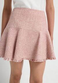 Rode en witte uitlopende rok van textuurstof; heeft een aansluitende taille en een franjeszoom.
