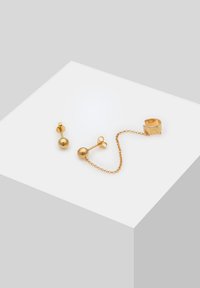Ensemble de bijoux dorés comprenant des boucles d'oreilles rondes à clous et un bracelet d'oreille en maillons avec une finition texturée. Design simple et moderne.