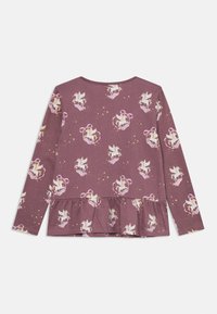 Violetti pitkähihaisessa paidassa on peplum-helma, jossa on valkoisia unicorn-kuvioita, nauhoja ja tähtiä leikkisässä koko-vaatteessa.