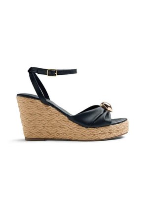 Sandalo zeppa in pelle nera con plateau in iuta intrecciata, cinturino alla caviglia con fibbia e decorazione in metallo dorato sulla fascia frontale.