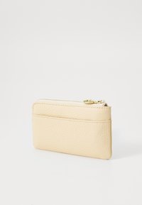 Læder kortholder i lys beige, med en tekstureret overflade, lynlåslukning øverst og en baglomme til ekstra kort.