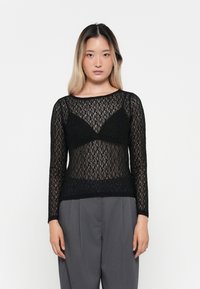 Schwarzes Spitzentop mit langen Ärmeln, das ein durchsichtiges Design und einen gewellten Saum aufweist. Der Ausschnitt ist rund und hat eine figurbetonte Silhouette.