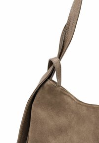 Sac à main en daim marron avec une bandoulière en cuir lisse. La bandoulière présente un détail en nœud, ajoutant de la texture au design global.