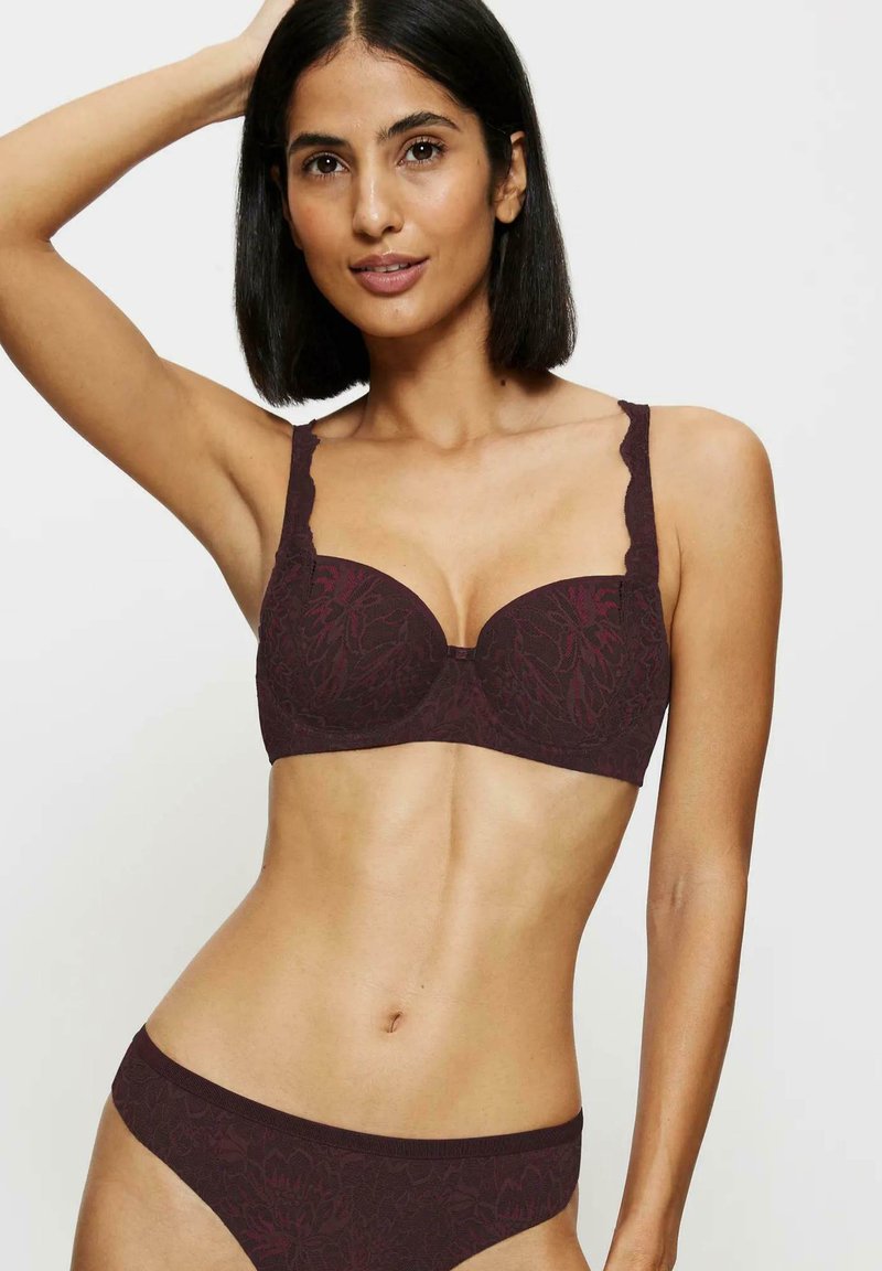 Bordowy koronkowy stanik z falbaniastymi ramiączkami, formowanymi miseczkami i kwiatowym wzorem. Pasujące bikini o niskim stanie w podobnej teksturze i kolorze.