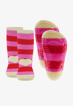 Chaussettes rayées avec des couleurs rose et rouge et un motif de cœur au niveau de la cheville. Semelles avec grips antidérapants ; texture douce et tricotée.