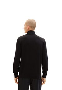 Schwarzer Rollkragenpullover mit langen Ärmeln, gerippten Bündchen und Saum, aus einem glatten, weichen Stoff gefertigt und mit einem lässigen Schnitt.