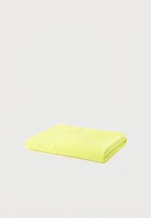 Serviette jaune vif pliée sur un fond gris clair uni, avec une texture visible et des bords nets.