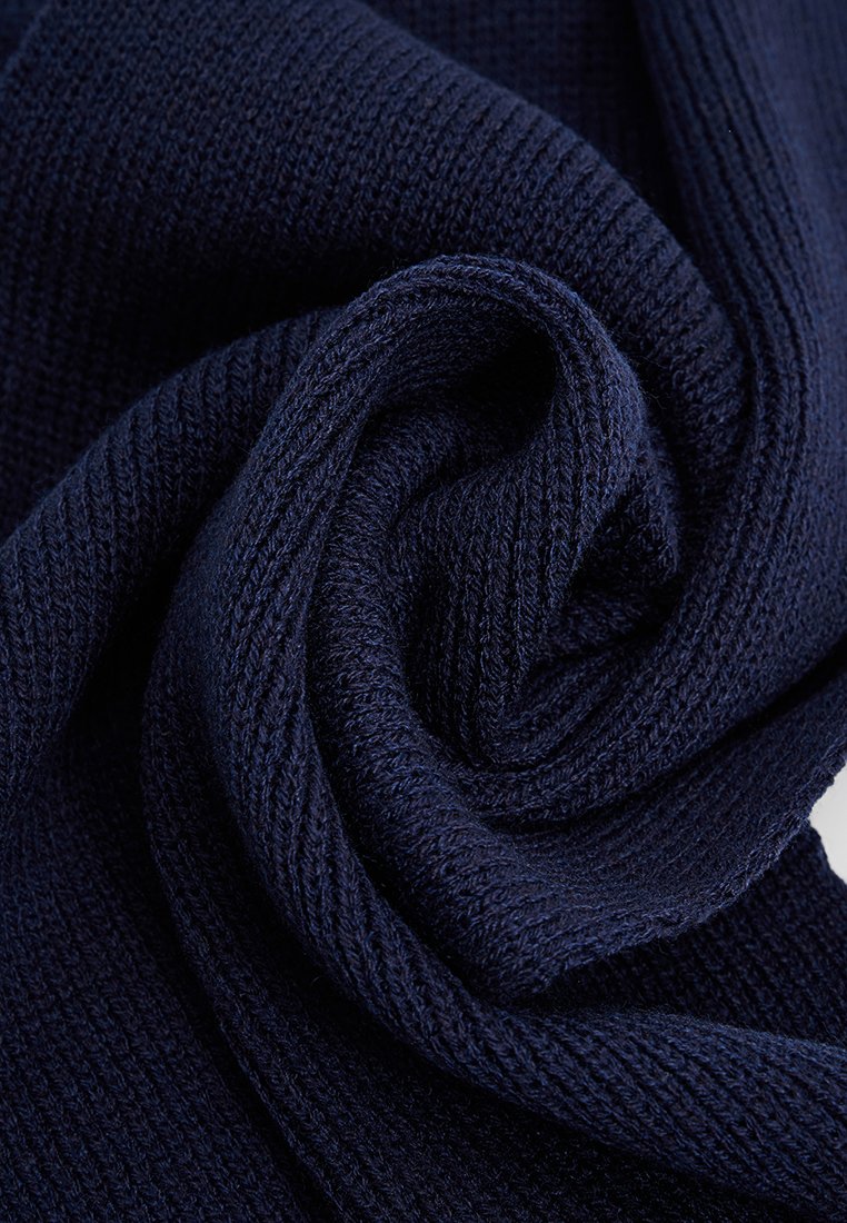 Marineblaues Strickgewebe mit einer strukturierten, gerippten Musterung, gefaltet, um seine Weichheit und Flexibilität zu zeigen. Eignet sich für Bekleidung oder Accessoires.