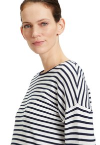 Gestreiftes Oberteil mit dunkelblau-weißen horizontalen Streifen, aus weichem Baumwollmaterial, weitem Ausschnitt und lässiger Passform mit überschnittenen Schultern.