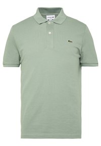 Polo-shirt vert clair à manches courtes avec deux boutons et un petit logo crocodile sur la poitrine gauche.