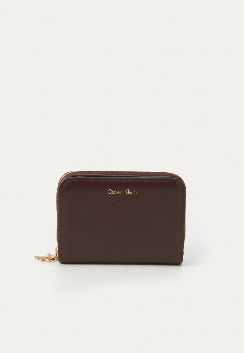 Portofel Calvin Klein din piele bordo, cu fermoare și logo aurii. Are o formă rectangulară și o textură netedă. Design compact și elegant.