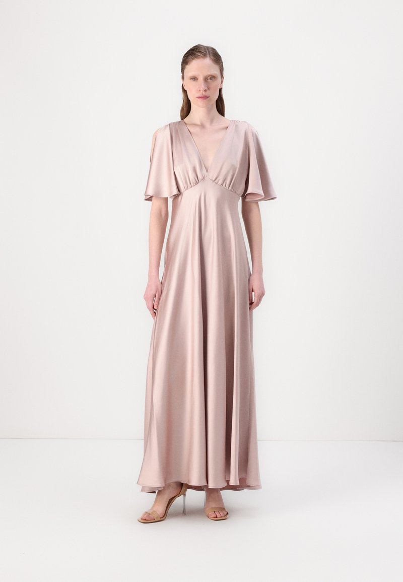 Abito lungo in satin rosa pallido con scollatura a V profonda e maniche svasate, design fluido e leggera lucentezza, abbinato a sandali con tacco beige.