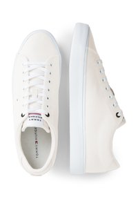 Zapatillas de lona blancas con un diseño de bajo, punta redonda y cordones blancos. Pequeño detalle del logo en la lengüeta y sutiles acentos en los laterales.
