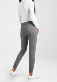 Gray cotton blend joggers with a tapered leg, elastic waistband, and ribbed cuffs. Paired with white sneakers and a fitted long-sleeve top.