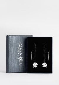 Örhängen i sterling silver med en klöverdesign, hängande på långa kedjor, presenterade i en svart sammetfodrad grå låda.