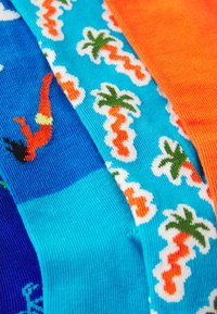 Chaussettes colorées avec une texture côtelée. Les motifs comprennent des sections orange et turquoise avec des palmiers et un contour de plongeur.
