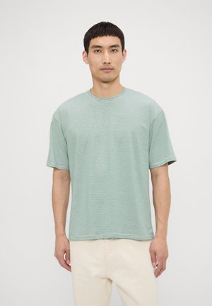Green striped T-shirt with short sleeves, crew neck, and a relaxed fit. Fabric appears soft with a subtle texture.
