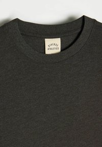 Czarny t-shirt w odcieniu ciemnoszarym z okrągłym dekoltem. Wykonany z miękkiego materiału, zawiera metkę z napisem "Diverse Athletics" na wewnętrznej stronie kołnierza.