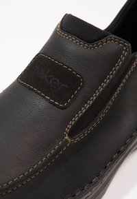 Zwarte leren instap schoen met elastische zijpanelen, contrasterende stiksels en een gestructureerde suede patch met het merklogo.