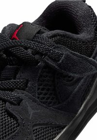 Musta urheilukenkä, jossa on verkko- ja mokkamateriaalia, mustat nauhat, pehmustettu kaulus ja kielen päällä punainen Jordanin logo.