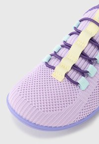 Gaiši violeta sporta apava ar sietveida tekstūru, kas aprīkota ar elastīgu sarkanu un gaiši zilu auklu, un elastīgu gumijas zolīti.