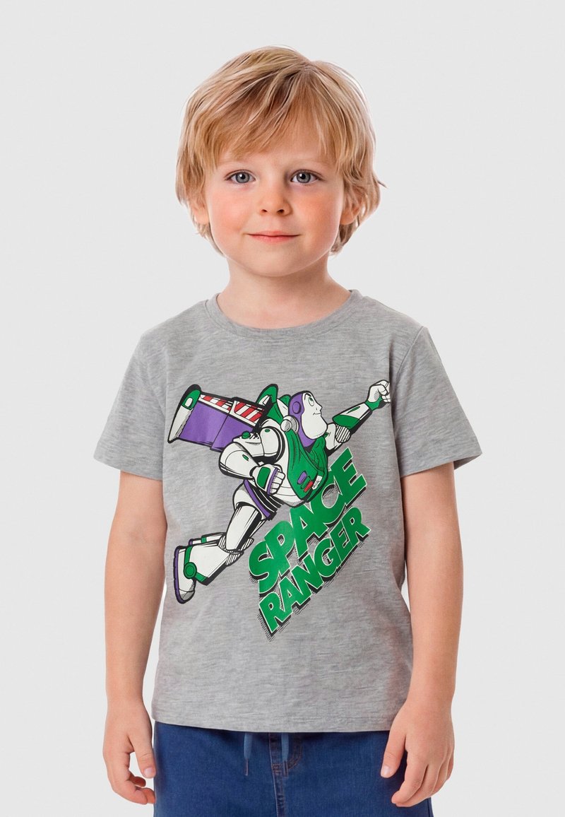 Jeune garçon aux cheveux blonds portant un t-shirt gris arborant un astronaute de dessin animé en train de voler et le texte « SPACE RANGER » en vert.