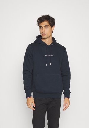 Felpa blu navy in misto cotone con cappuccio regolabile e tasca frontale. Presenta un logo bianco sulla parte anteriore e polsini a costine.