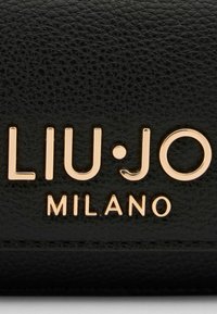 Schwarze, strukturierte Lederbörse mit eingeprägtem Logo in goldfarbener Schrift: "LIU·JO MILANO" mit glänzender Oberfläche.
