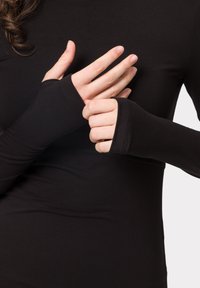 Camiseta negra de manga larga con puños para el pulgar. Tejido suave y elástico con un diseño sin costuras y una textura suave, ideal para superponer.