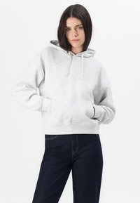Grå hoodie med snod, kenguruficka, ribbade ärmslut och nederkant. Matchad med mörkblå jeans i en figurnära stil.