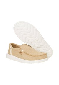 Zapatos beige de tipo slip-on, hechos de tela texturizada, con una suela de goma blanca con un patrón de olas y un pequeño acento de logo.