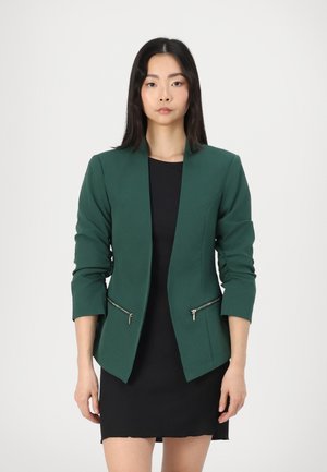 Blazer verde con un diseño ajustado, mangas largas y bolsillos laterales con cremallera. Confeccionado en una tela suave, presenta un cuello afilado y líneas limpias.