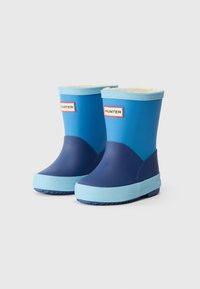 Botas de chuva de borracha azuis com uma secção inferior azul-marinho, sola azul clara e um forro suave. Apresentam o logótipo "HUNTER" numa etiqueta branca.